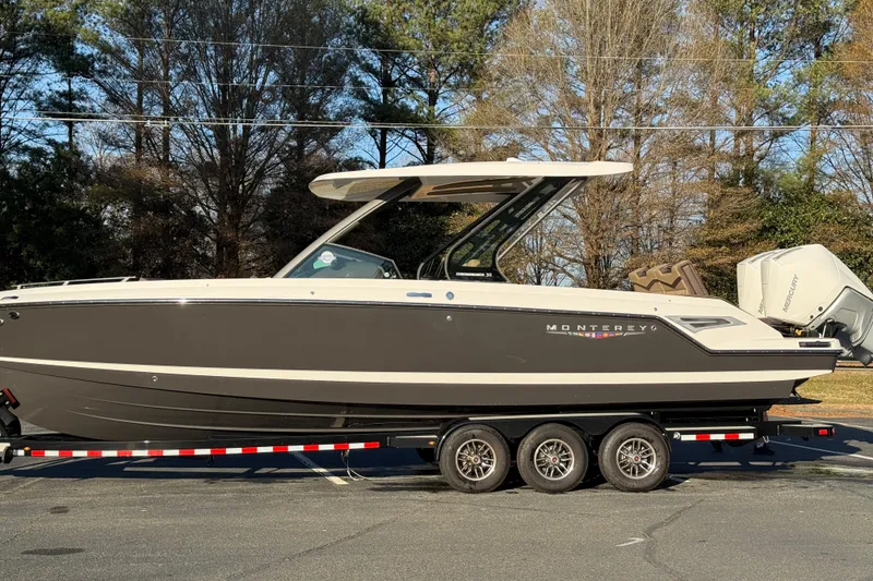 Slide: The Image of 2026 Monterey Elite 30 OB boat on trailer, parked outdoors, side view. - 13