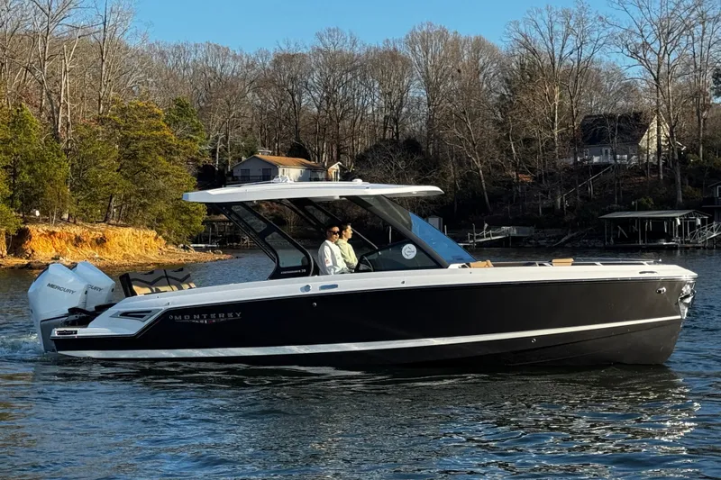 Slide: The Image of 2026 Monterey Elite 30 OB boat cruising on a serene lake with wooded shoreline. - 2