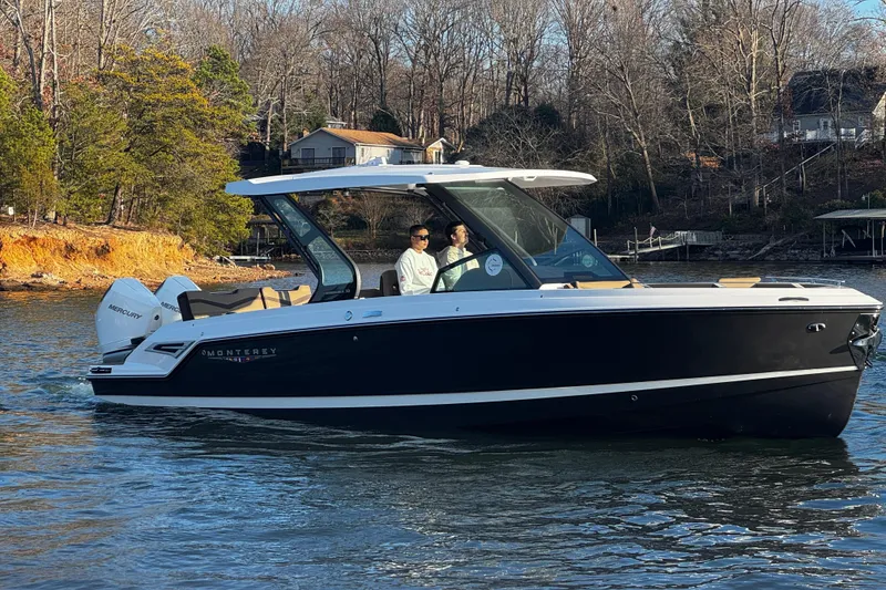 Slide: The Image of 2026 Monterey Elite 30 OB boat cruising on a serene lake with wooded shoreline. - 4