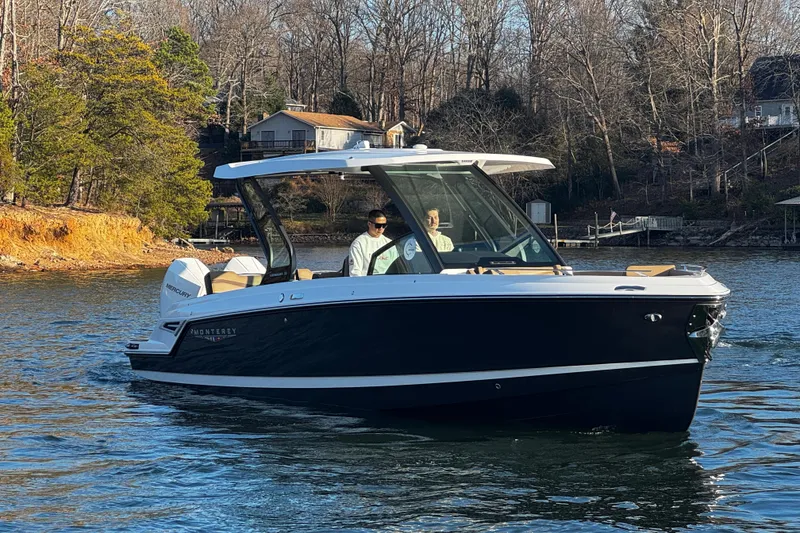 Slide: The Image of 2026 Monterey Elite 30 OB boat cruising on a scenic lake with wooded shoreline. - 5