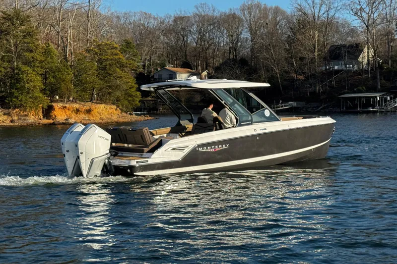 Slide: The Image of 2026 Monterey Elite 30 OB boat cruising on a scenic lake with wooded shoreline. - 6