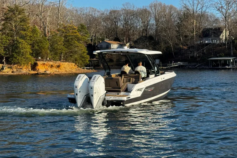 Slide: The Image of 2026 Monterey Elite 30 OB boat cruising on a scenic lake with passengers onboard. - 7