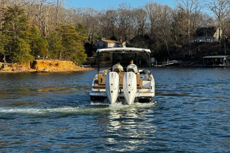 Slide: The Image of 2026 Monterey Elite 30 OB boat cruising on a scenic lake with wooded shoreline. - 8