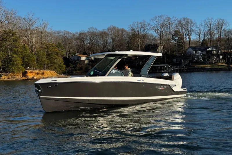 Slide: The Image of 2026 Monterey Elite 30 OB boat cruising on a serene lake with wooded shoreline. - 9