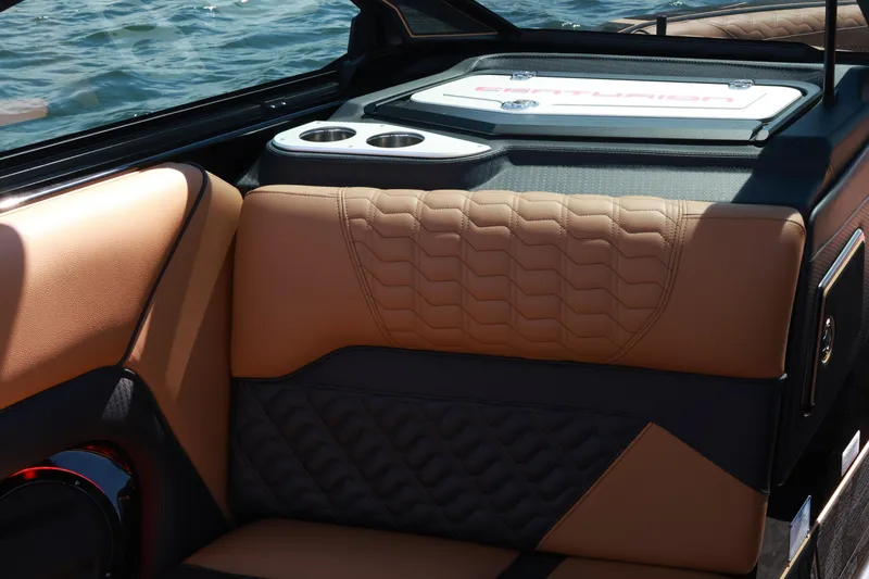 Slide: The Image of 2024 Centurion Ri265 boat interior with tan and black leather seating, cup holders, and water view. - 13