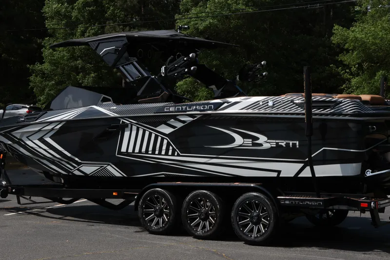 Slide: The Image of 2024 Centurion Ri265 boat with sleek black and white design on a trailer. - 21