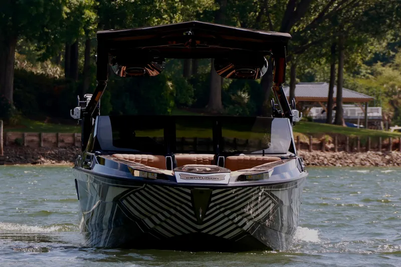 Slide: The Image of 2024 Centurion Ri265 boat cruising on a scenic lake with lush greenery. - 4