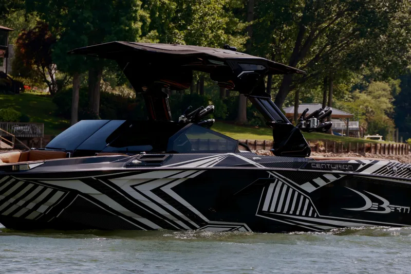 Slide: The Image of 2024 Centurion Ri265 boat with sleek black and white design on a scenic lake. - 6
