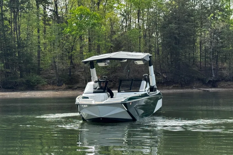Slide: The Image of 2020 Nautique Super Air Nautique G23 Paragon on a serene lake with forest backdrop. - 2