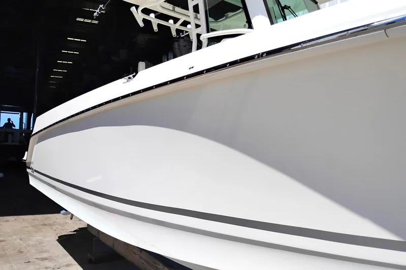 Slide: The Image of 2018 Boston Whaler 280 Outrage boat side view in a dimly lit indoor setting. - 10