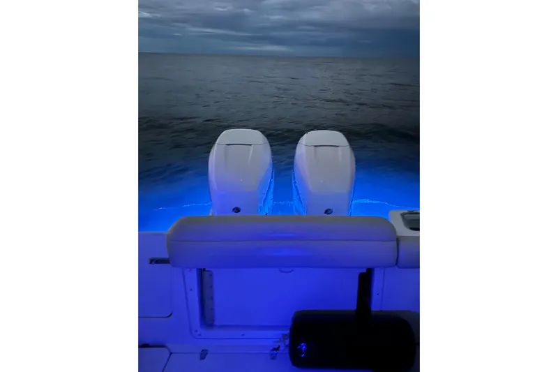 Slide: The Image of Boston Whaler 280 Outrage 2018 with illuminated twin engines at dusk on the ocean. - 39