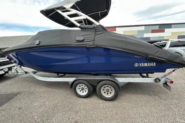 The Image of 2022 Yamaha Boats 252SD, blue, covered, on trailer, parked outdoors. - 0