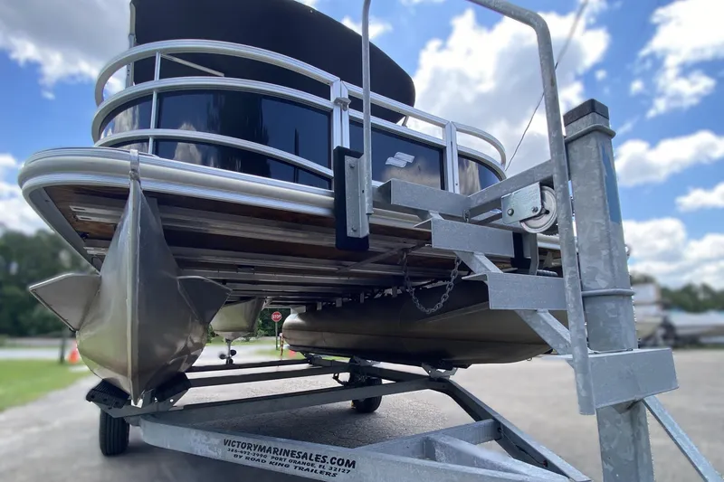 Slide: The Image of 2023 Starcraft SF 16 DLX pontoon boat on trailer under a blue sky. - 13