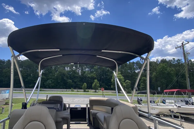 Slide: The Image of 2023 Starcraft SF 16 DLX pontoon boat with canopy under a clear blue sky. - 4