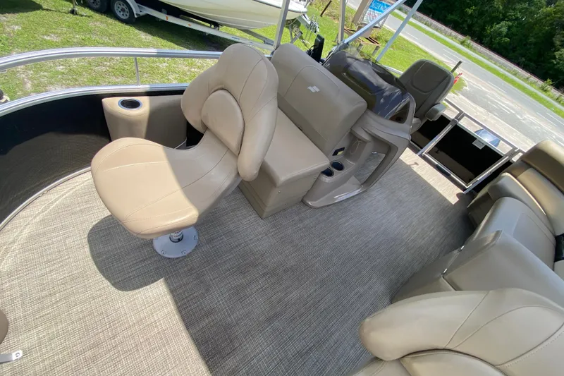 Slide: The Image of 2023 Starcraft SF 16 DLX pontoon boat interior with beige seating and steering console. - 5
