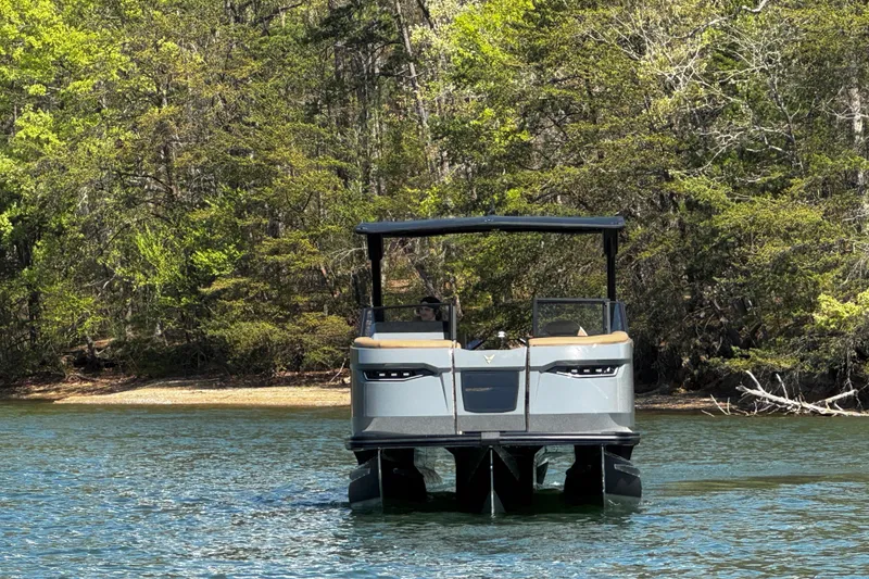 Slide: The Image of 2026 Revel RS25L pontoon boat on a serene lake with lush forest backdrop. - 4