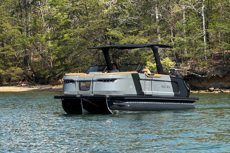 Slide: The Image of 2026 Revel RS25L boat cruising on a serene lake with lush forest backdrop. - 5