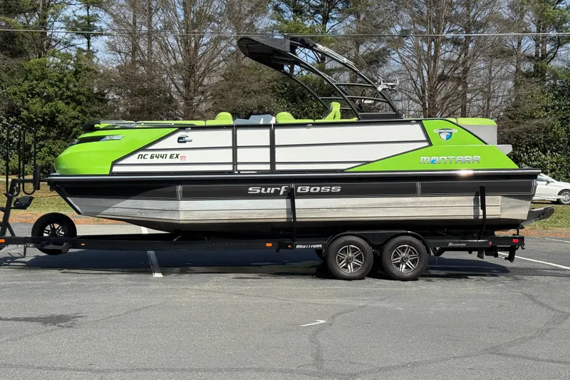 Slide: The Image of 2021 Montara 25 Surf Boss boat on trailer, vibrant green accents, parked outdoors. - 10