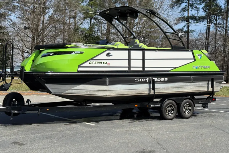 Slide: The Image of 2021 Montara 25 Surf Boss boat in vibrant green on a trailer, parked outdoors. - 11
