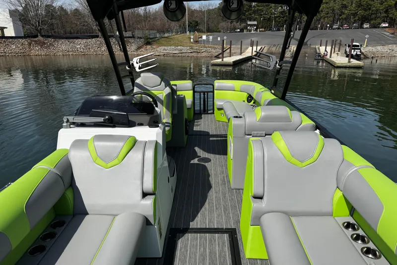 Slide: The Image of 2021 Montara 25 boat interior with green and gray seating, docked on a calm lake. - 13