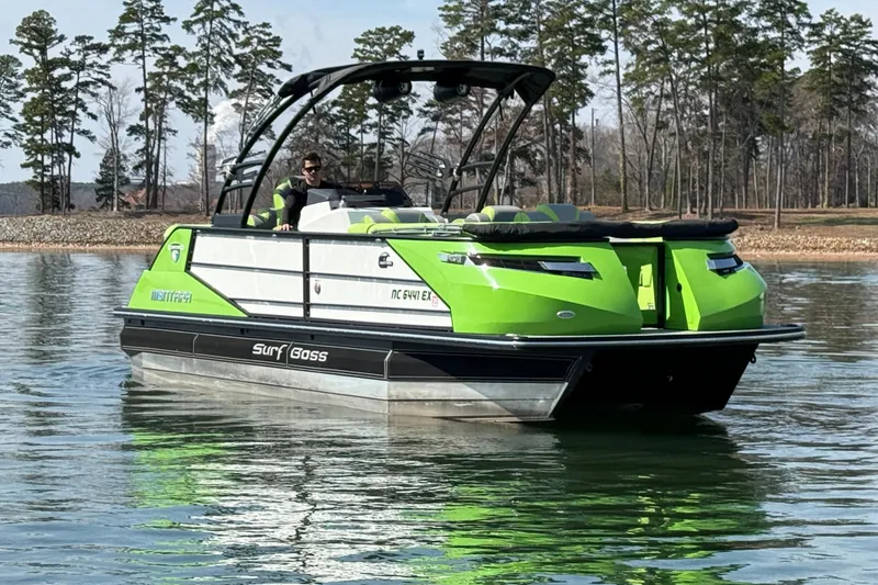 Slide: The Image of 2021 Montara 25 boat in vibrant green on a calm lake, surrounded by trees. - 2