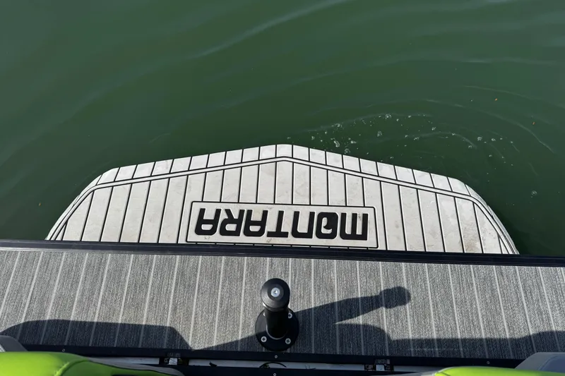 Slide: The Image of 2021 Montara 25 boat swim platform on water, featuring striped design and logo. - 22