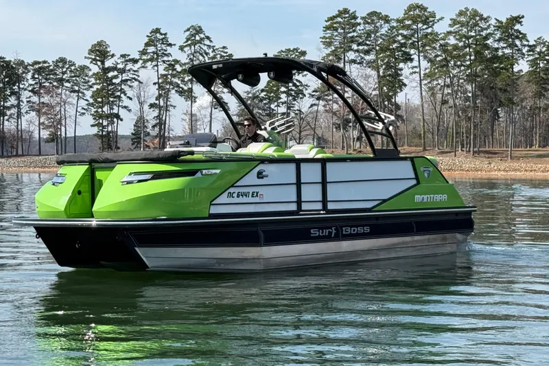 Slide: The Image of 2021 Montara 25 boat in vibrant green on a serene lake with trees in the background. - 5