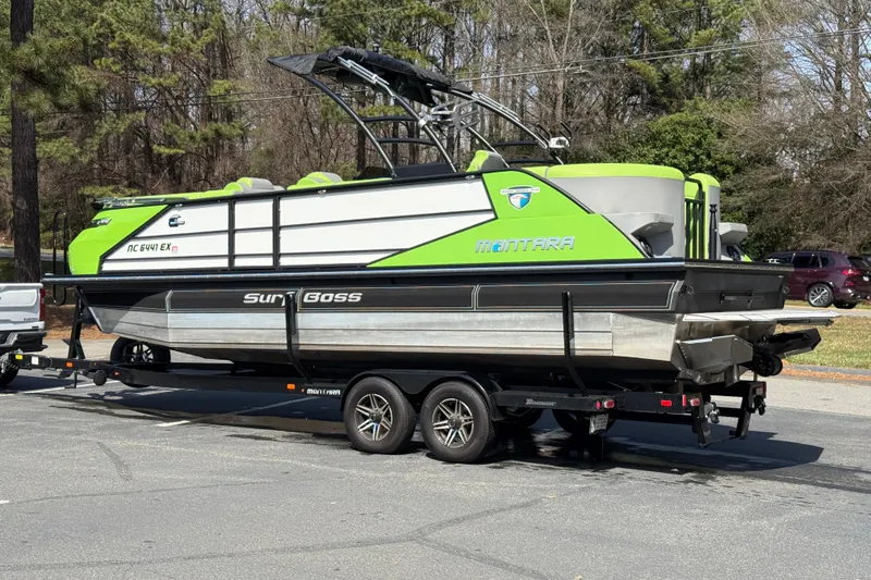 Slide: The Image of 2021 Montara 25 boat on trailer, vibrant green accents, parked outdoors. - 9