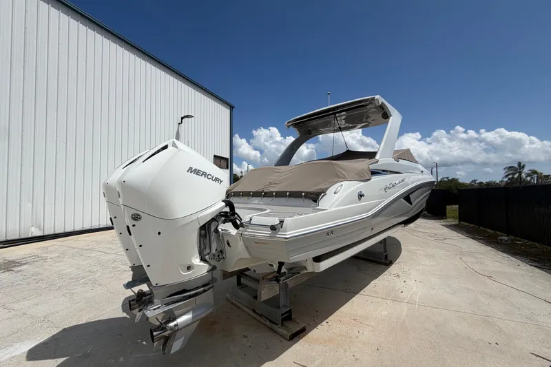 Slide: The Image of 2019 Crownline Eclipse E295 XS boat with Mercury engine, docked outdoors under clear sky. - 2