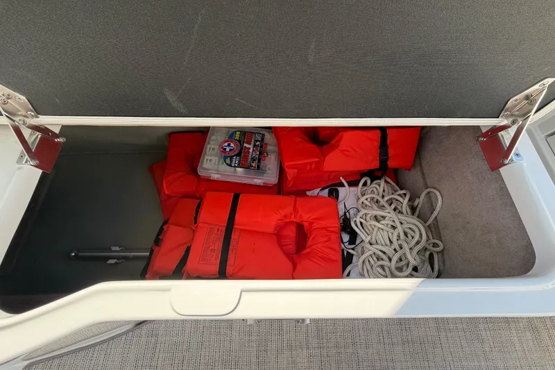 Slide: The Image of Storage compartment in 2019 Crownline Eclipse E295 XS with life jackets, rope, and first aid kit. - 37