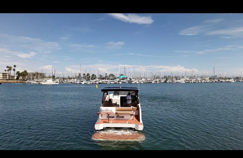 Slide: The Image of A modern boat cruising on calm water, with a harbor full of boats in the background. - 7
