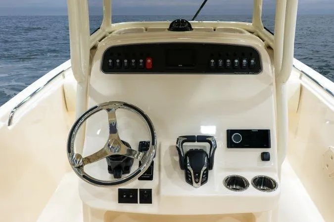 Slide: The Image of 2025 Grady-White Fisherman 257 helm with steering wheel and control panel, ocean backdrop. - 6