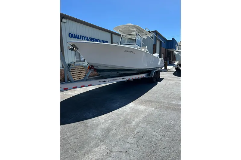 The Image of 2018 Sportsman Open 282 Center Console boat on trailer, parked outside service facility. - 1