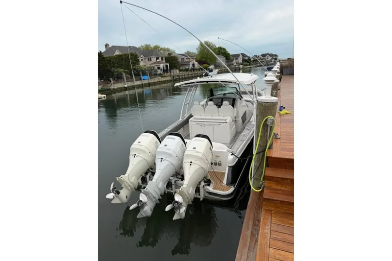 Slide: The Image of 2016 Chris-Craft Catalina 34 docked, featuring triple outboard engines, in a serene marina setting. - 1