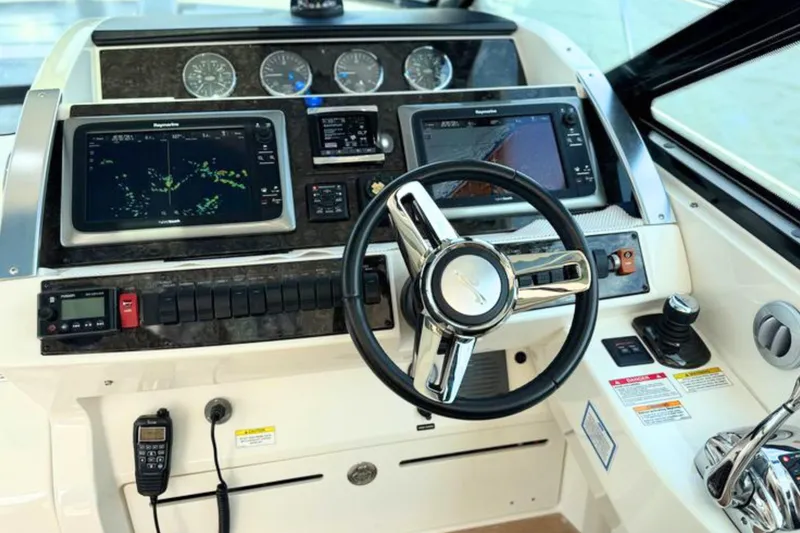 Slide: The Image of Cockpit of 2013 Sea Ray 450 Sundancer with navigation screens and steering wheel. - 26