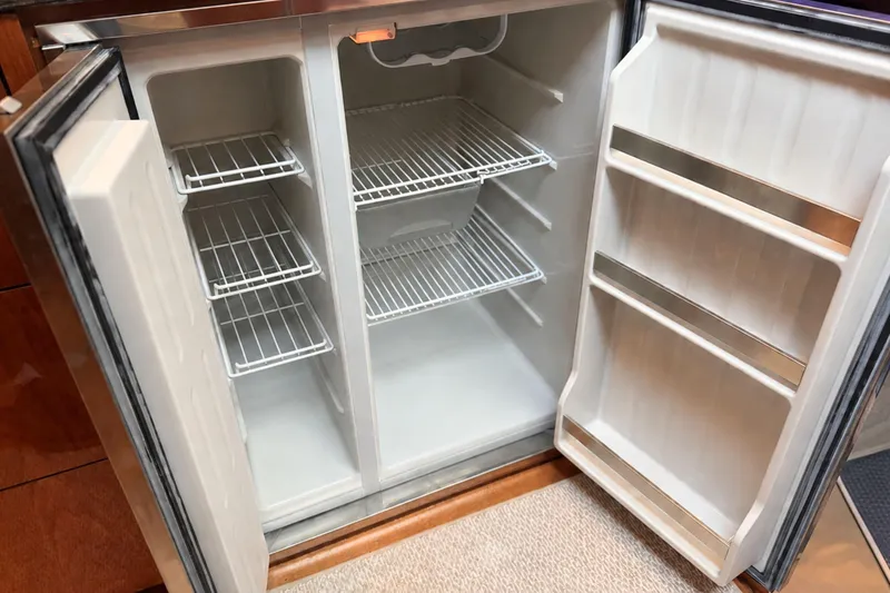 Slide: The Image of Open refrigerator inside a 2013 Sea Ray 450 Sundancer yacht, featuring wire shelves and door storage. - 38