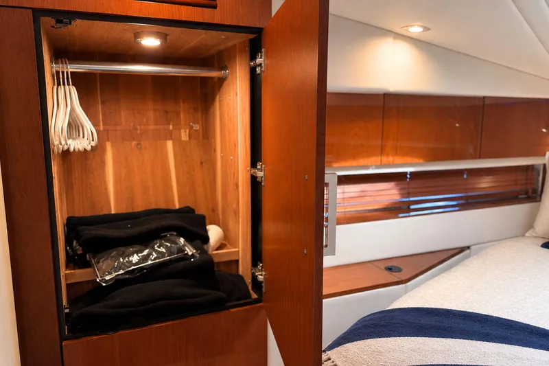 Slide: The Image of Interior of 2013 Sea Ray 450 Sundancer yacht with open wooden closet and cozy bedroom. - 53
