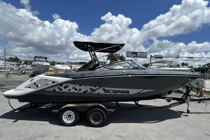 Slide: The Image of 2019 Scarab 255 ID boat on trailer under cloudy sky at marina. - 1