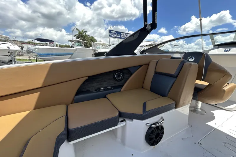 Slide: The Image of 2019 Scarab 255 ID boat interior with tan and black seating under a blue sky. - 18