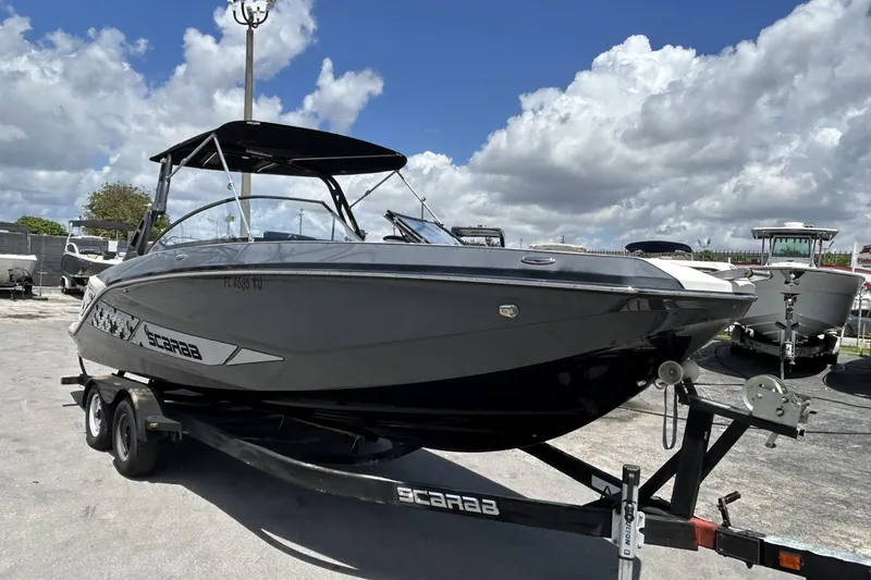Slide: The Image of 2019 Scarab 255 ID boat on trailer under cloudy sky. - 2