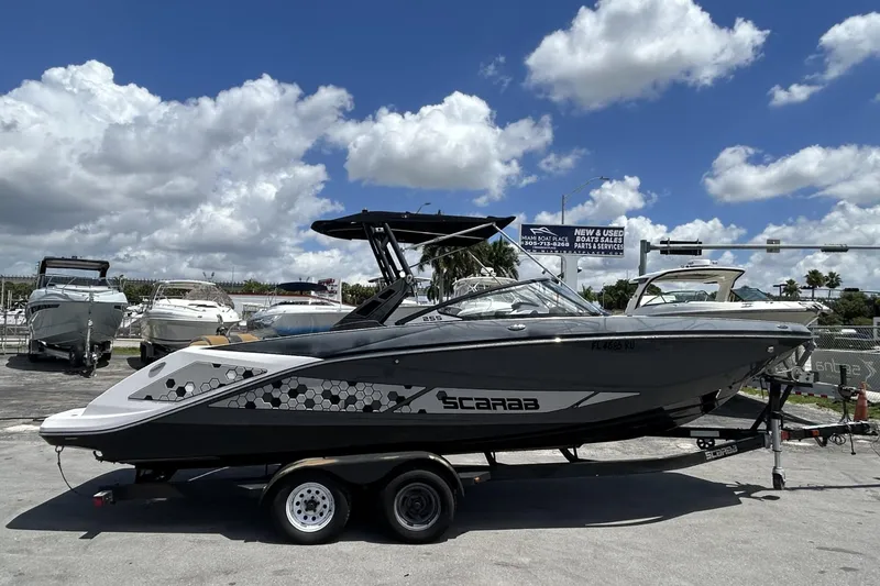 Slide: The Image of 2019 Scarab 255 ID boat on trailer under blue sky at marina. - 4