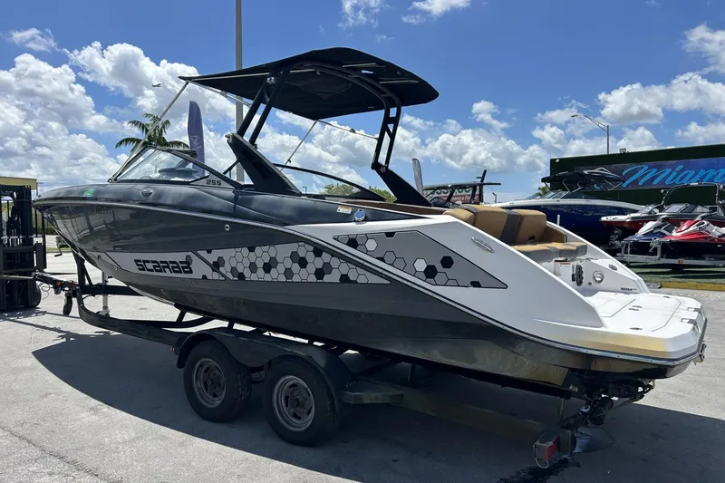 Slide: The Image of 2019 Scarab 255 ID boat on trailer under clear blue sky. - 5