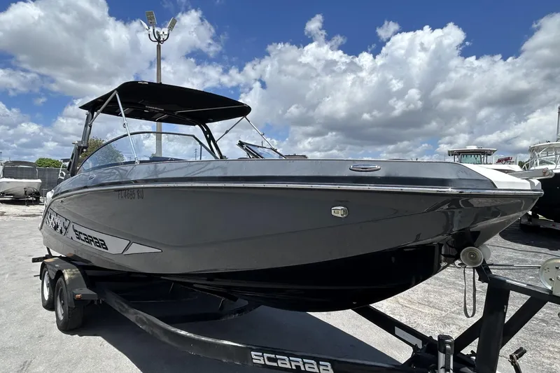 Slide: The Image of 2019 Scarab 255 ID boat on trailer under a cloudy sky. - 6
