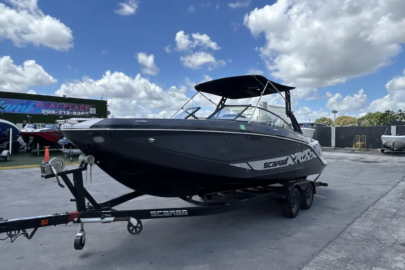 Slide: The Image of 2019 Scarab 255 ID boat on trailer at Miami Boat Place under blue sky. - 8