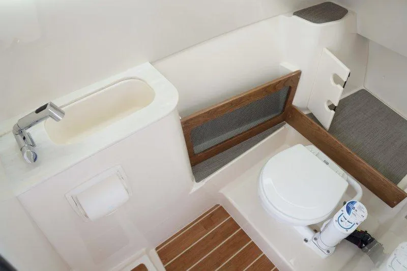 Slide: The Image of 2027 Grady-White Freedom 285 boat bathroom with sink, toilet, and wooden accents. - 9