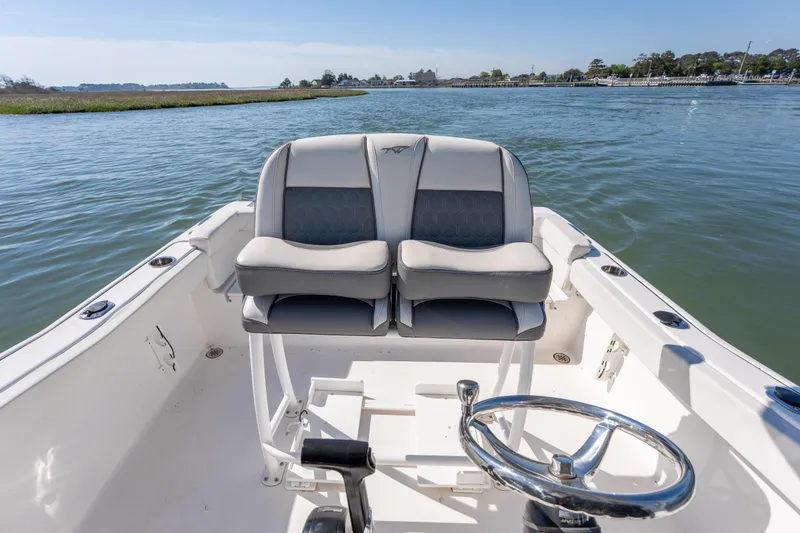 Slide: The Image of 2021 Tidewater 220 LXF boat interior with dual seats and steering wheel on calm water. - 12