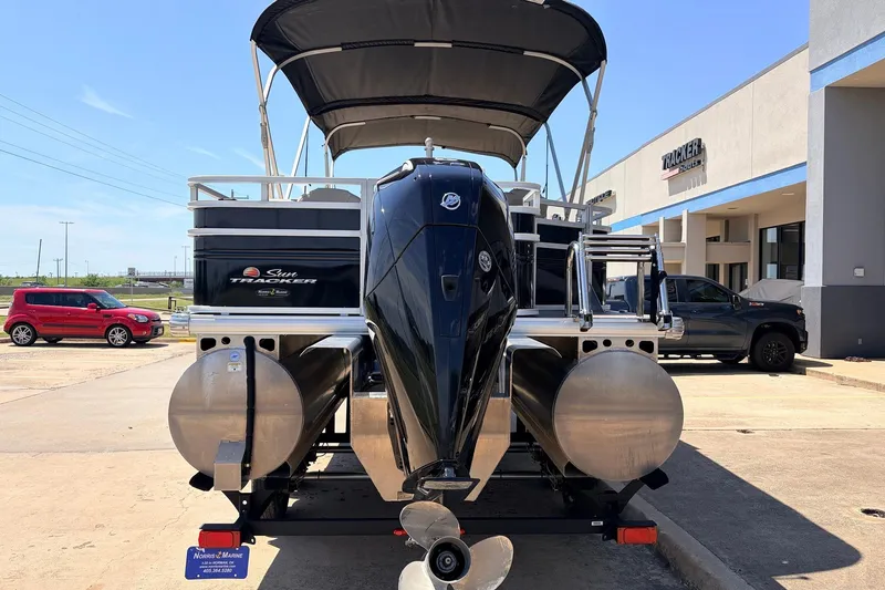 Slide: The Image of 2024 Sun Tracker SportFish 22 XP3 pontoon boat with outboard motor, parked outside dealership. - 6