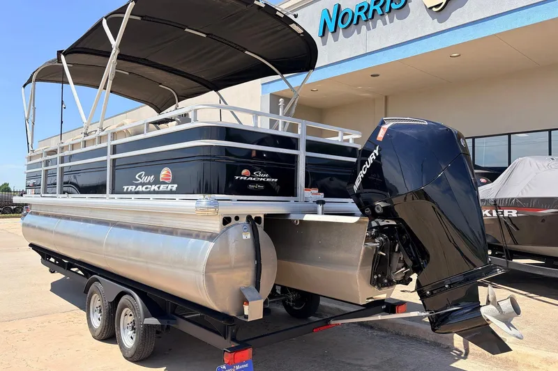 Slide: The Image of 2024 Sun Tracker SportFish 22 XP3 pontoon boat with Mercury outboard motor, parked outside dealership. - 7