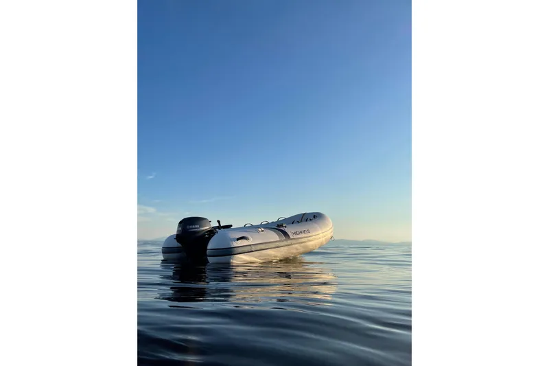 Slide: The Image of 2026 Highfield UltraLite 290 inflatable boat on calm water under clear blue sky. - 8