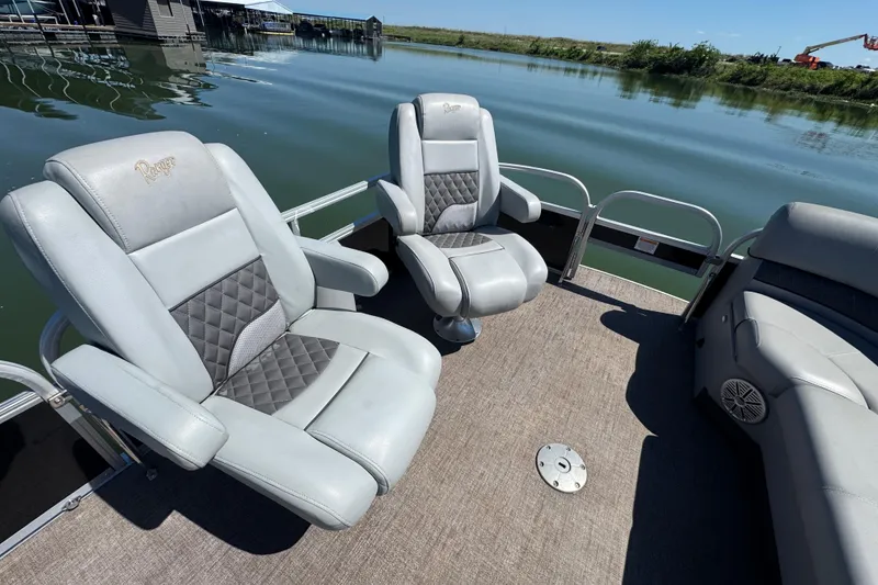 Slide: The Image of 2022 Ranger 223FC boat interior with plush seating on a calm lake. - 11